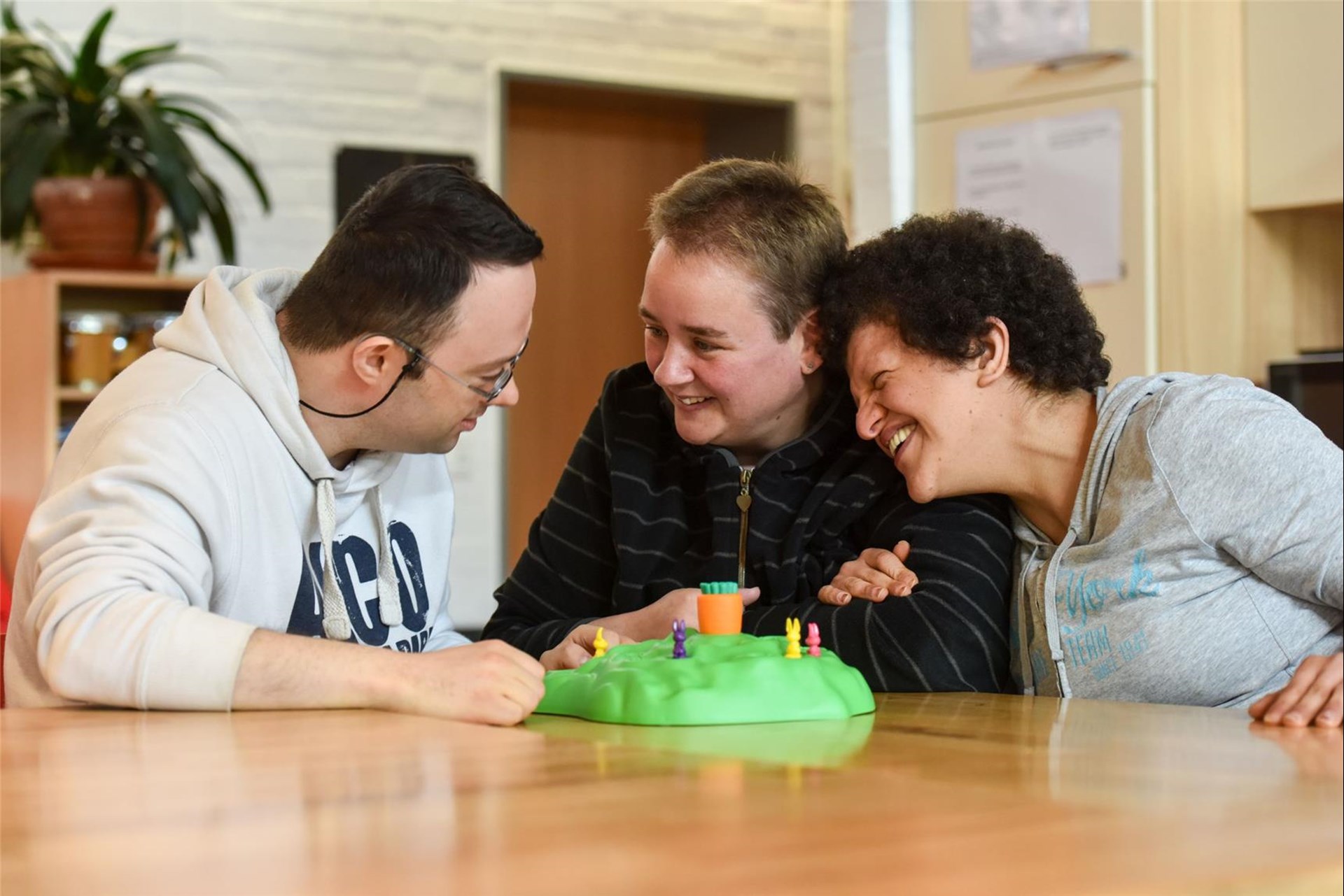 Betreuerin hat Spaß beim Spielen mit zwei Menschen mit Behinderung