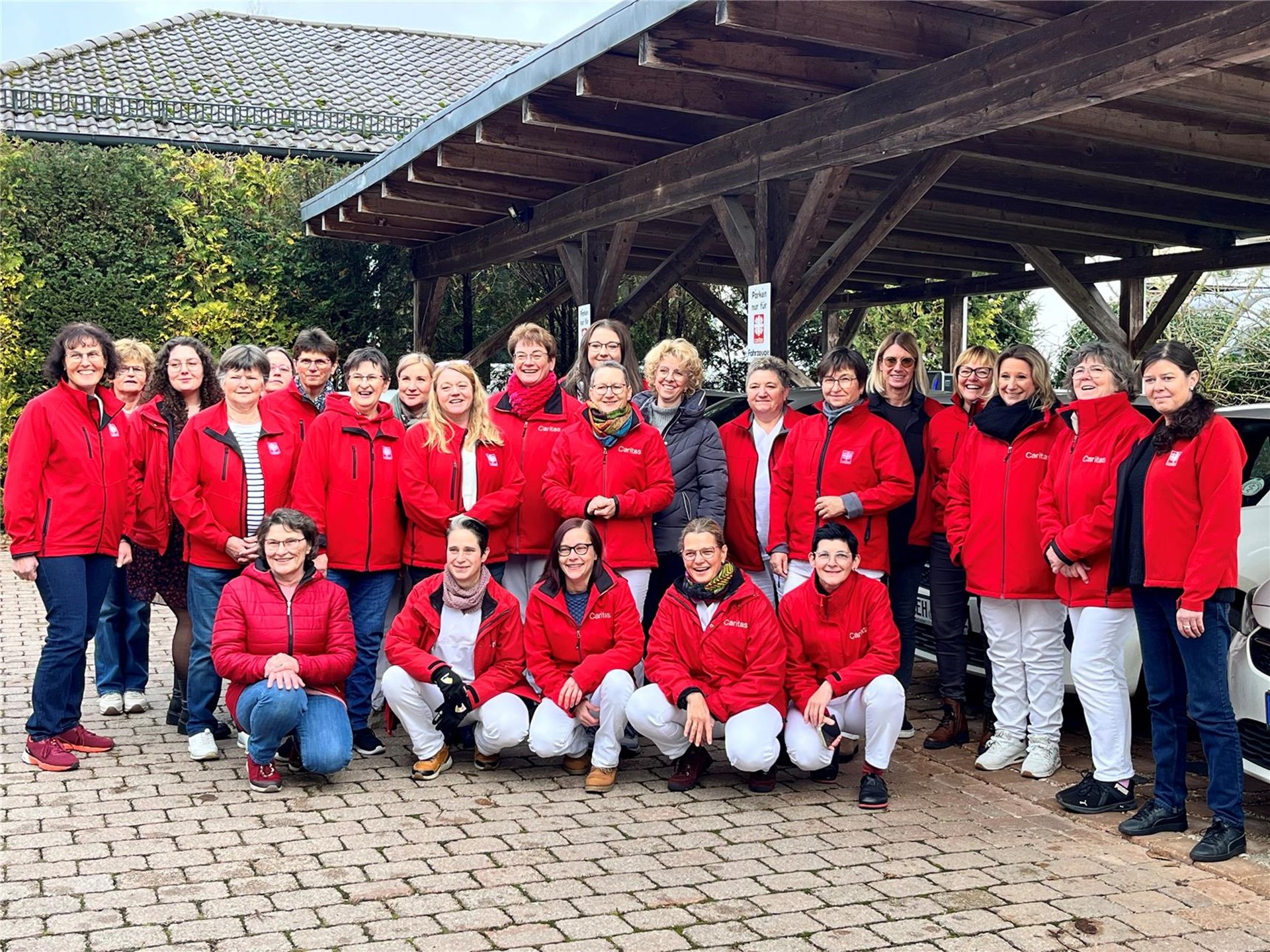 Die Mitarbeitenden der Caritas Sozialstation Abensberg in Pflegeuniform gekleidet, stehen gemeinsam vor dem Carport.