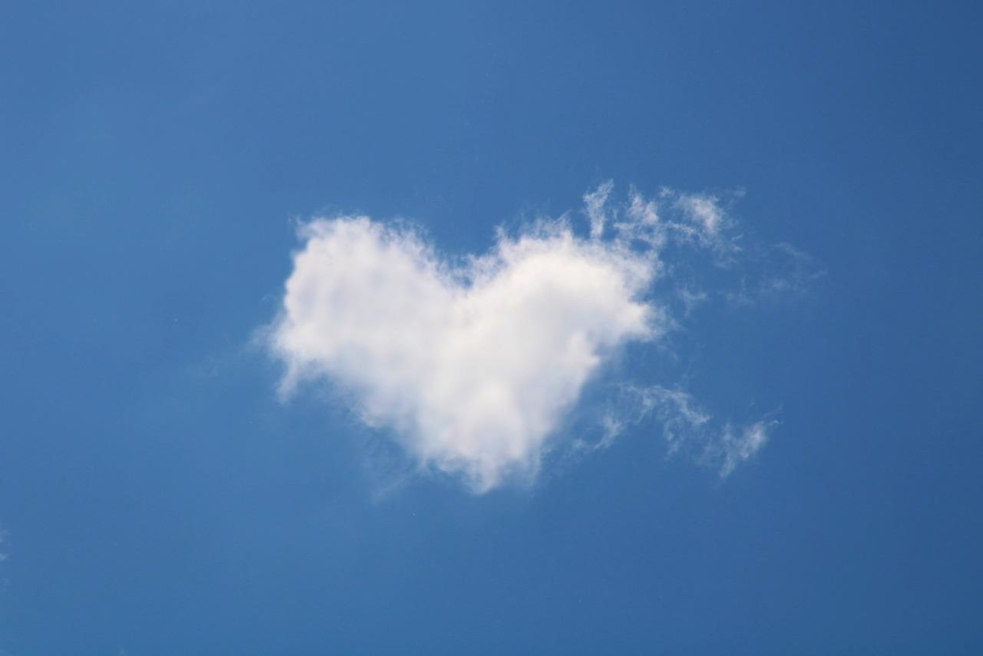 Bild einer herzförmigen weißen Wolke vor strahlend blauem Himmel