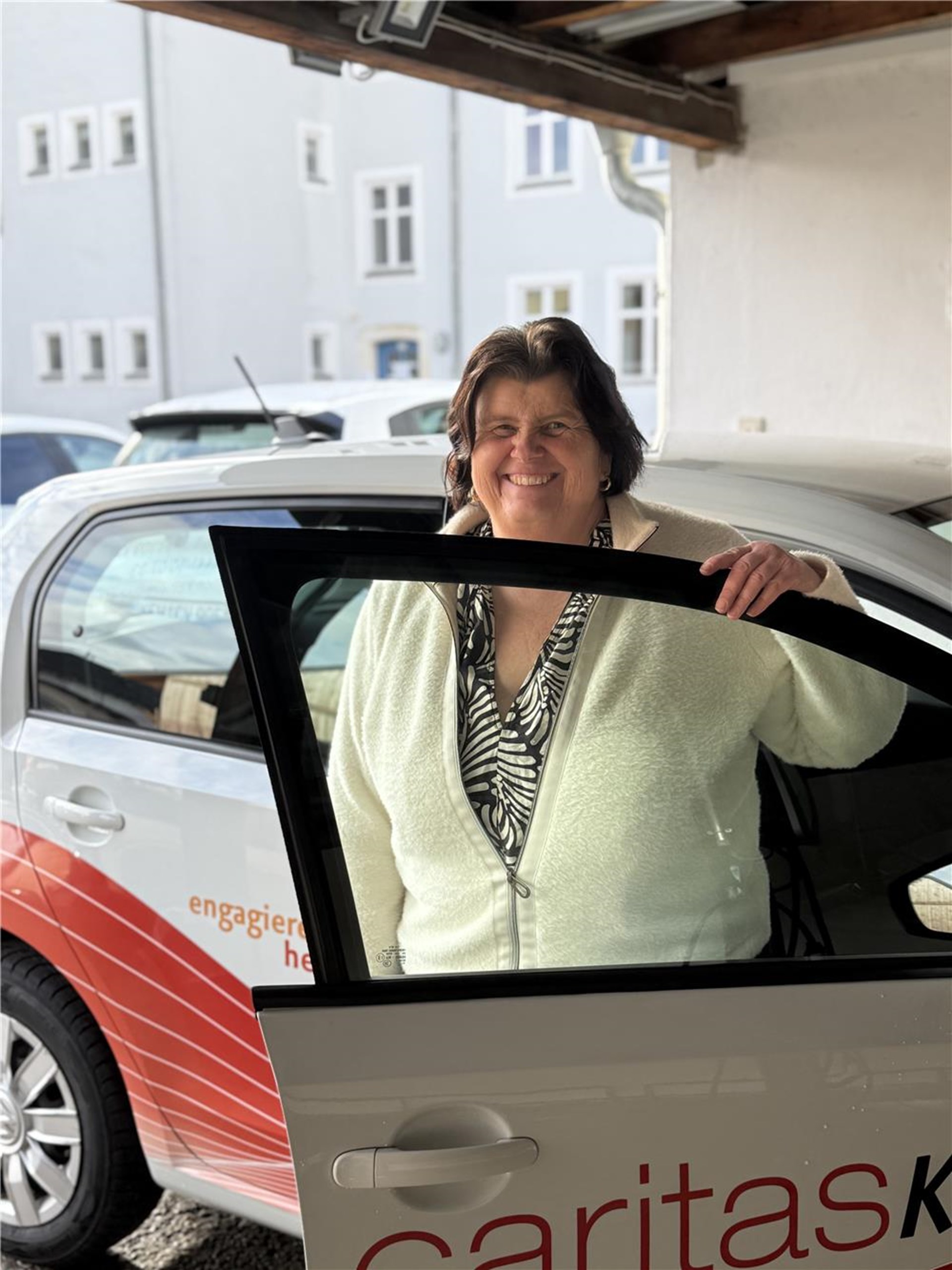 Eine Frau steht in einer geöffneten Fahrertür